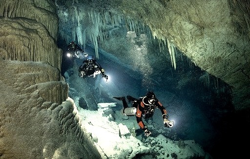 Three divers swim through the water-filled passages below the island of Bermuda